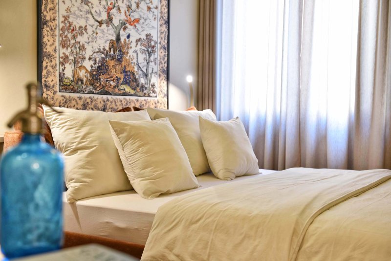 Letto matrimoniale grande con cuscini morbidi e un quadro d'arte dietro alla parete