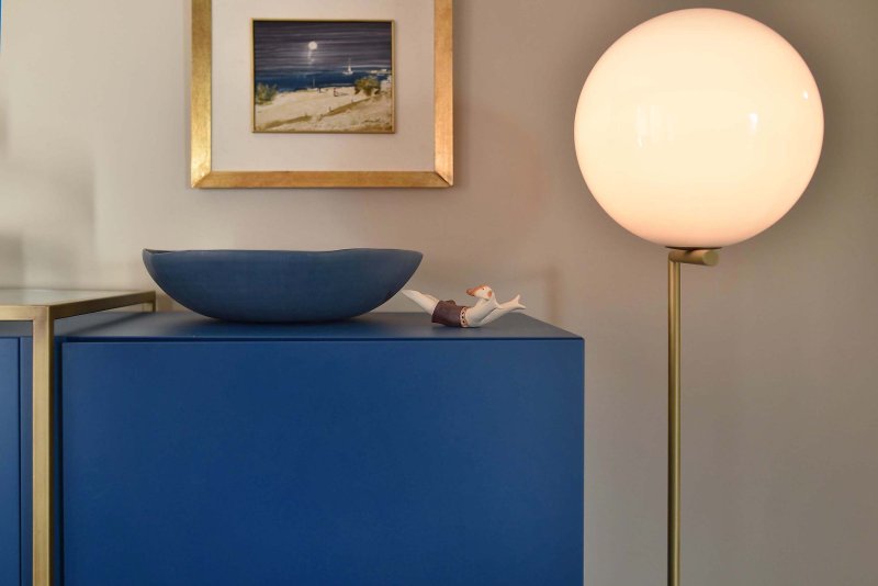 Kleines Männchen und große blaue Schüssel als Dekoration auf blauem Regal