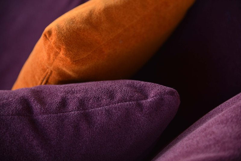 Dettaglio di tre cuscini di velluto in viola e arancione