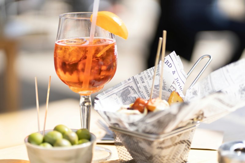Aperol Spritz, olive e altri snack su un tavolo al sole
