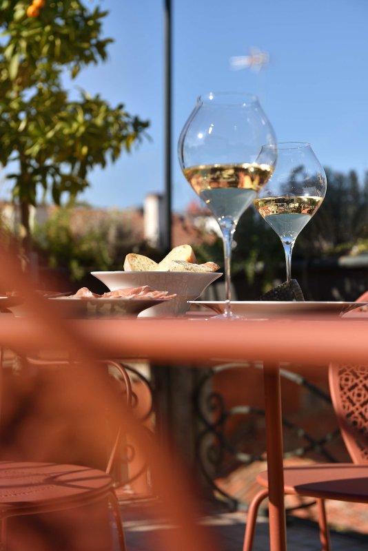 Weingläser mit Weißwein auf sonniger Terrasse auf kleinem orangefarbenem Tisch