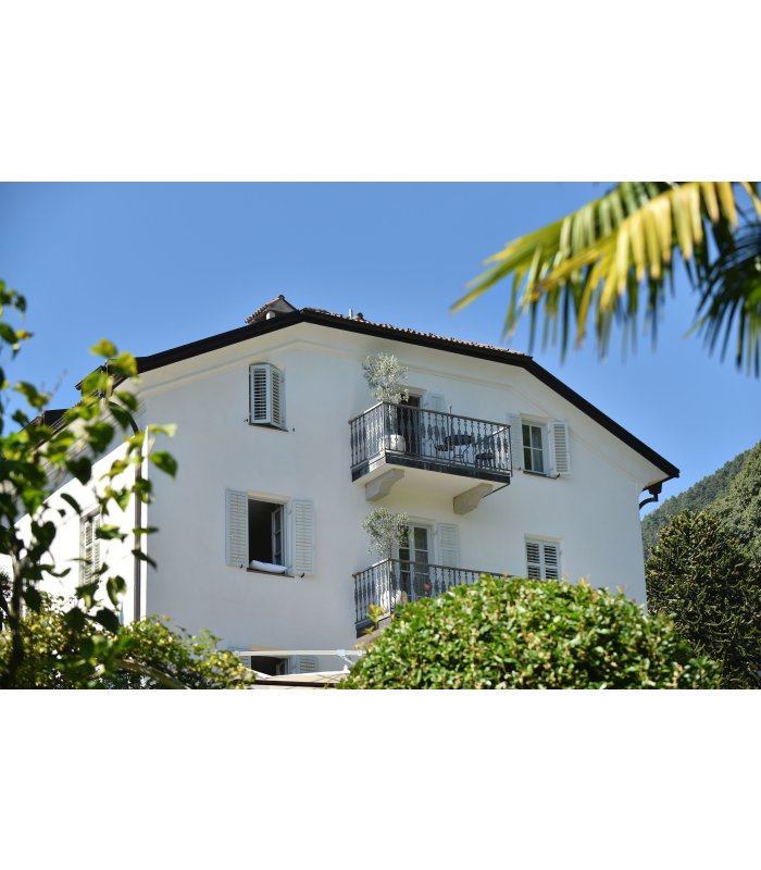 Haus mit weißer Fassade und geöffneten Fenstern und Balkon.