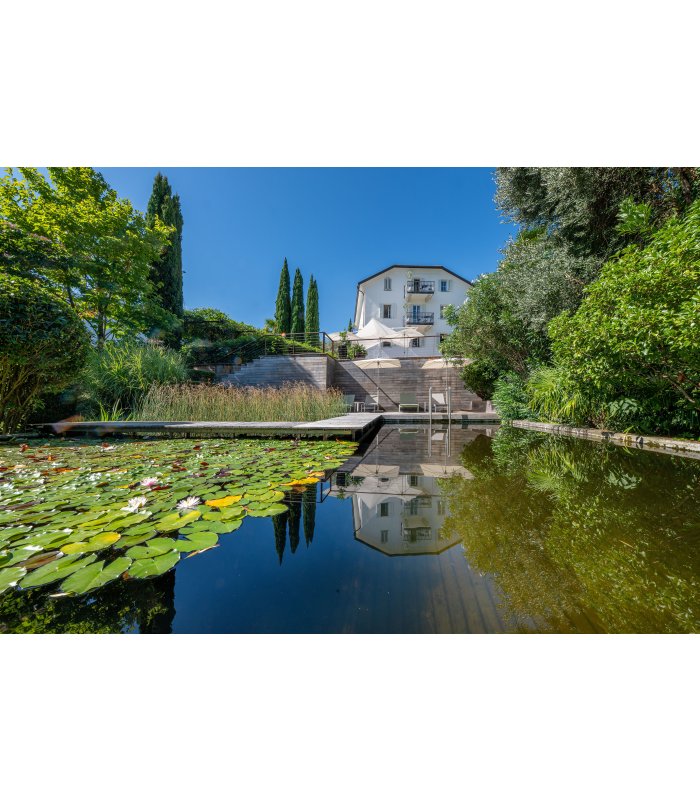 Naturbadeteich in Algund in dem sich das Haus spiegelt.