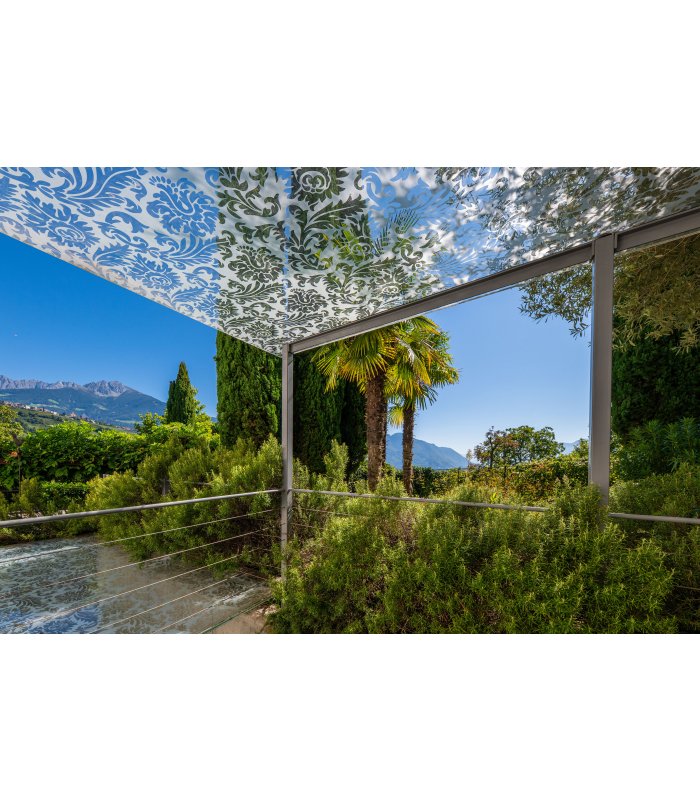 Sonnige Terrasse in Algund mit Palmen unter klarem Himmel.