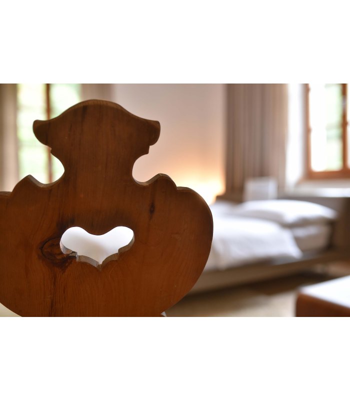 Detail eines geschwungenen Holzstuhls mit Herz in der Rückenlehne