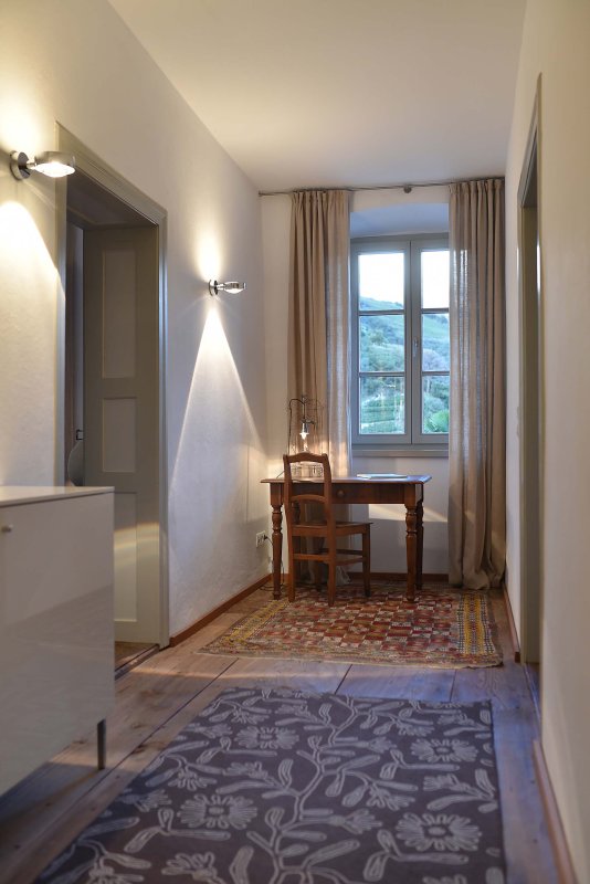 Hell erleuchteter Gang mit hellem Teppichboden, am Ende ein großes Fenster