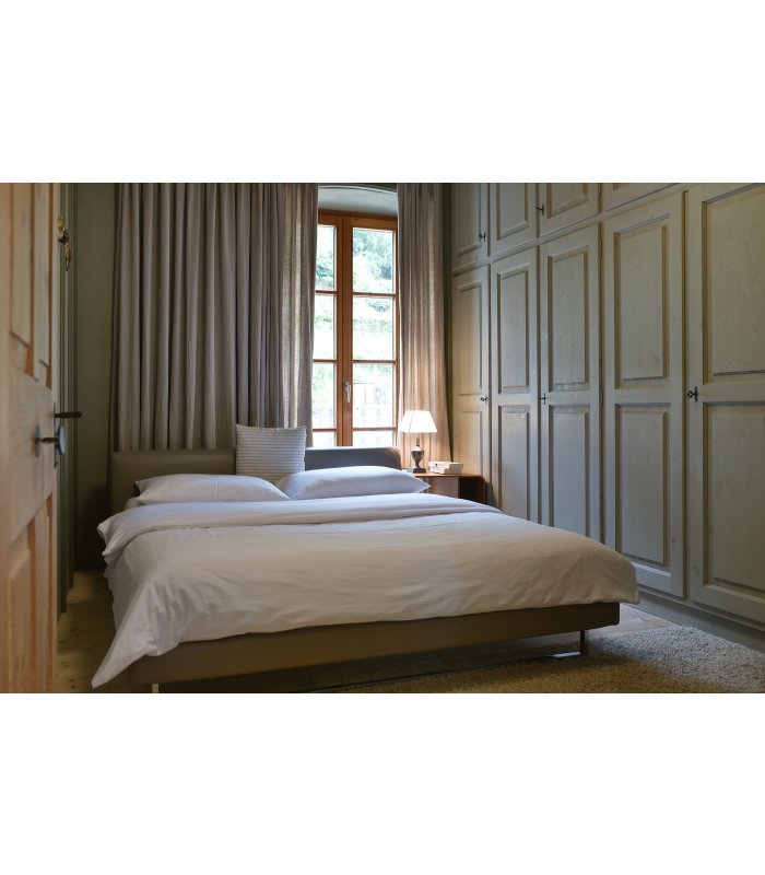 Helles Schlafzimmer mit Doppelbett, großem Kleiderschrank an der Wand und weitläufigem Fenster