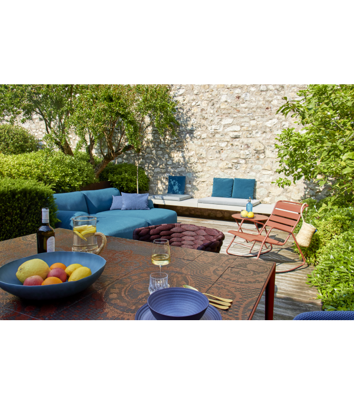 Bunte Gartenmöbel auf einer modernen Terrasse mit einer Schüssel voller Obst und vielen Pflanzen
