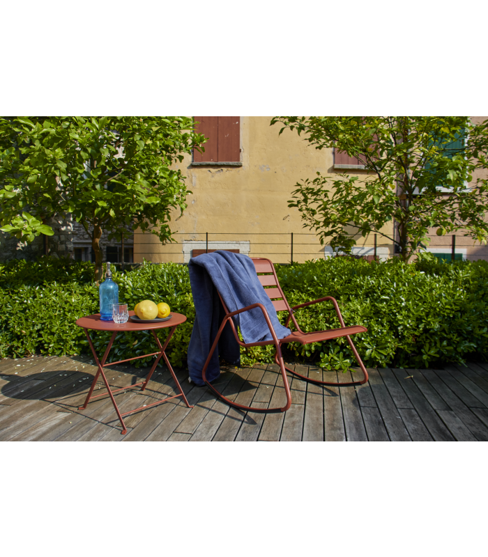 Ein roter Gartenstuhl auf einer Terrasse mit einem Handtuch und einem roten Beistelltisch mit einem Teller Zitronen