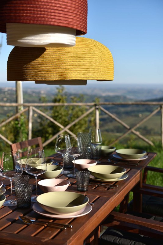 Gedeckter Holztisch mit Ausblick auf eine hügelige Landschaft