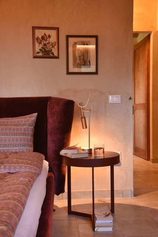 Comodino con lampada moderna, libro e bicchiere d'acqua accanto a un letto accogliente