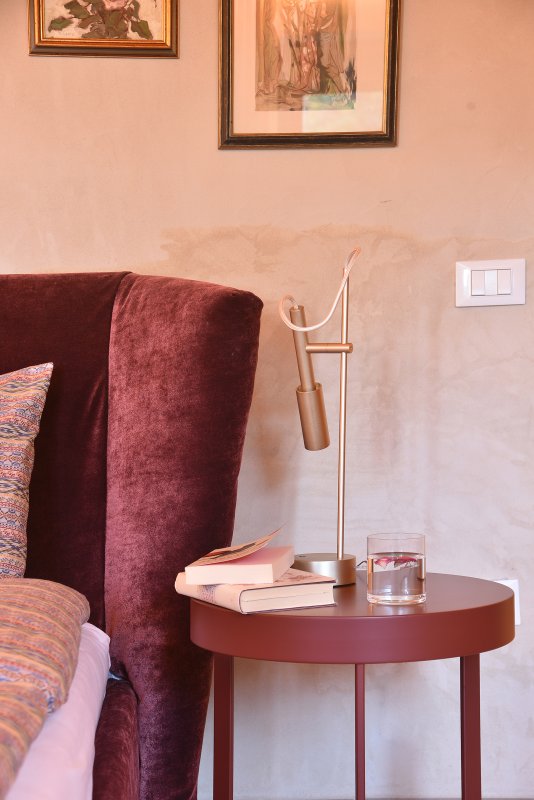 Comodino con lampada moderna, libro e bicchiere d'acqua accanto a un letto accogliente