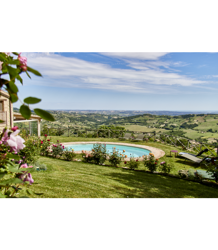 Pool mit Panoramablick auf eine grüne Hügellandschaft unter blauem Himmel