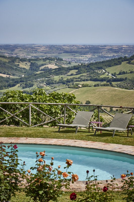 Round pool overlooking a vast hilly landscape under a blue sky