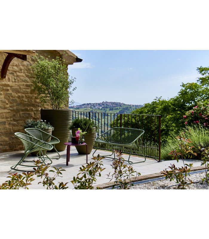 Sunny terrace with green chairs, plant pots, and a view of the hills