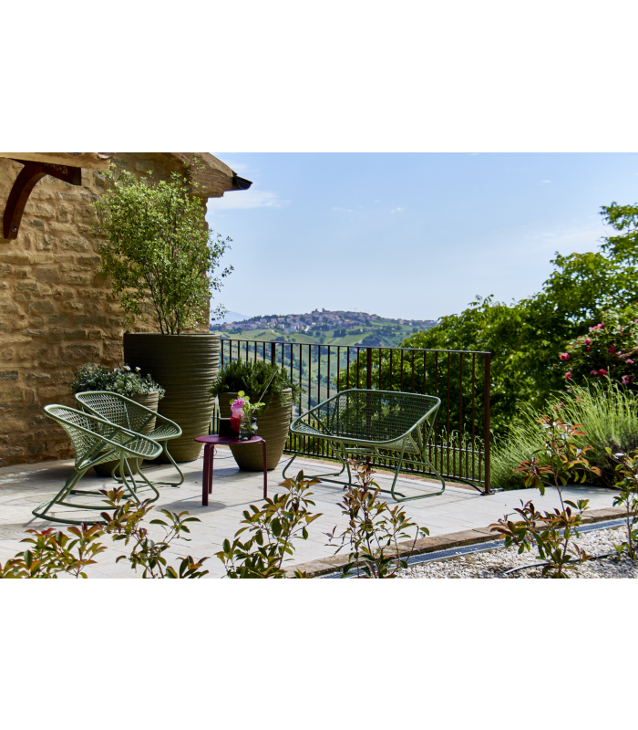 Die sonnige Terrasse mit einem kleinen Tisch und türkisen, stylischen Stühlen, die in der Sonne glänzen