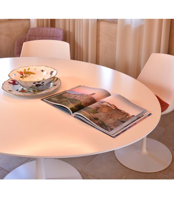 Tavolo rotondo bianco con rivista aperta e stoviglie decorative