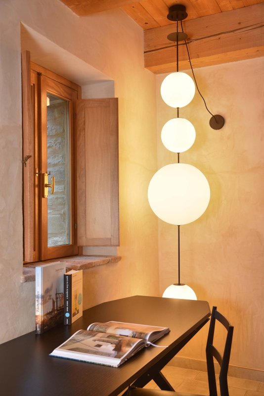  Tavolo nero con rivista aperta accanto a una finestra in legno e lampade a sospensione rotonde