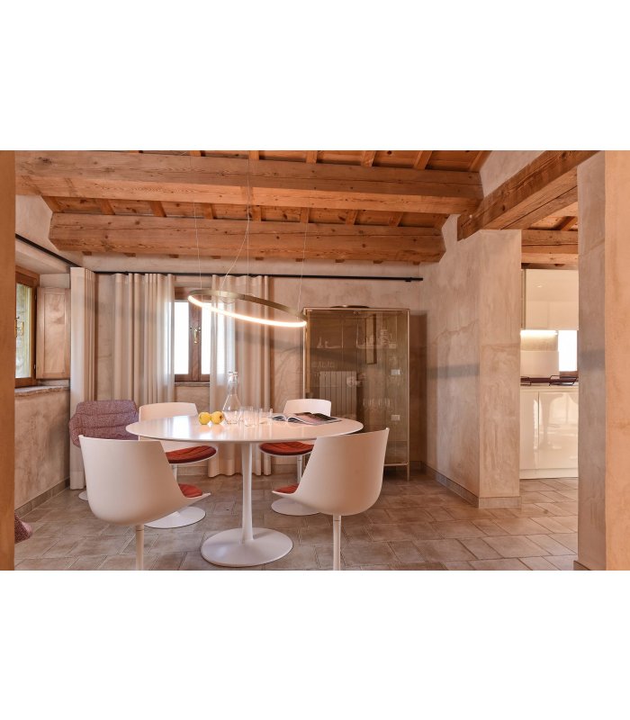 Accogliente zona pranzo con tavolo rotondo bianco e sedie moderne in una stanza con travi in legno