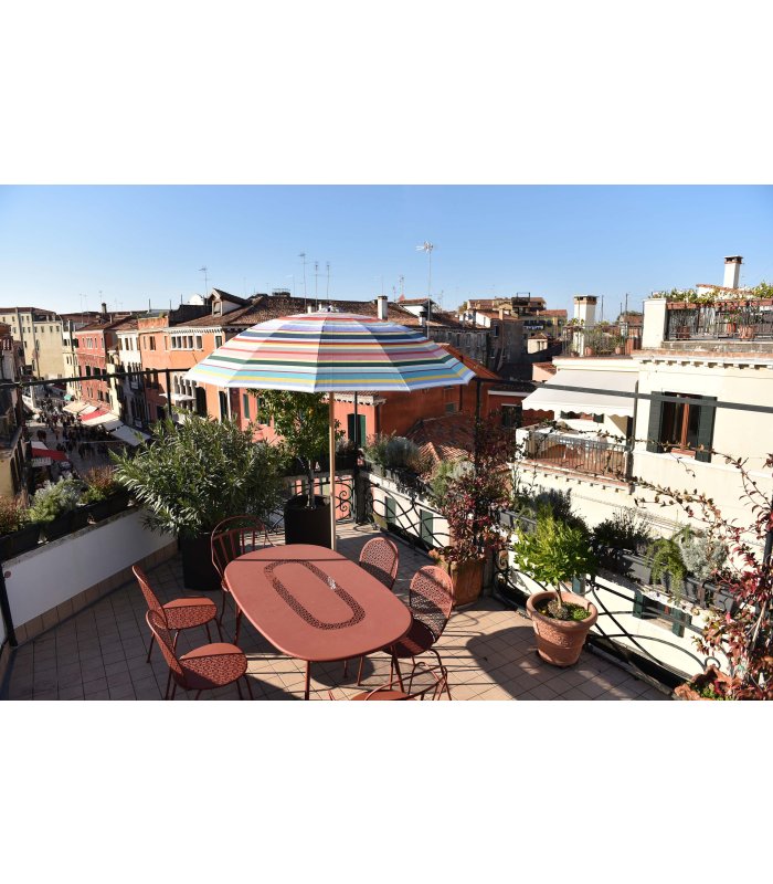 Blick von der Terrasse mit orangem Tisch und buntem Sonnenschirm