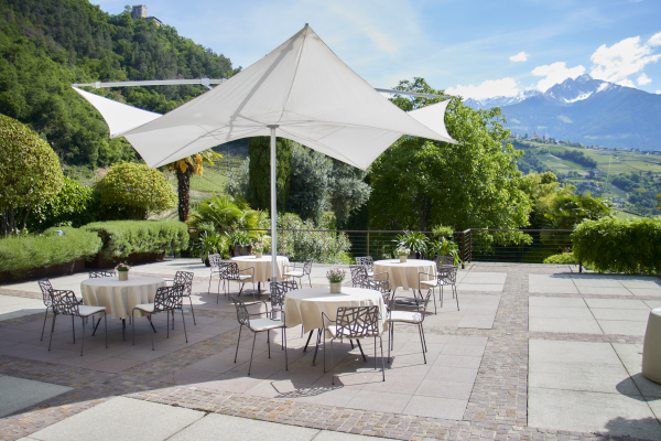 Terrasse mit Tischen Sonnenschirm und Stühlen und blauer Himmel