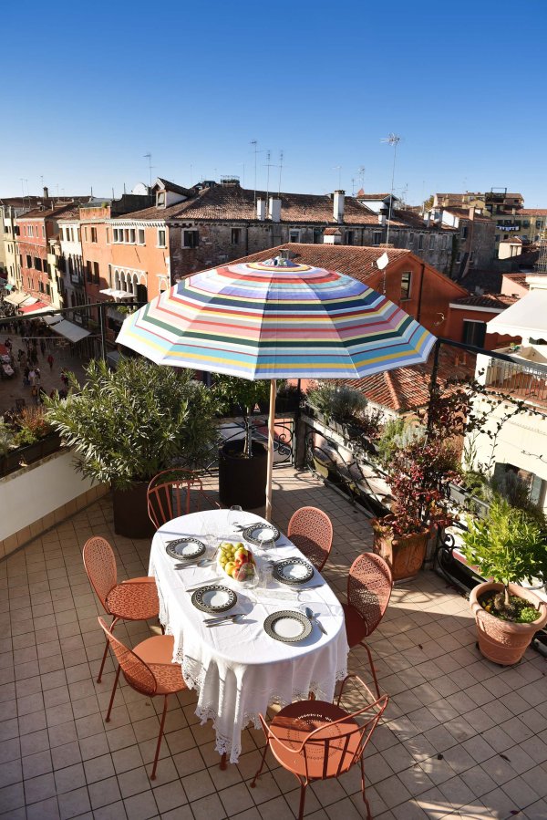 Ein gedeckter Tisch unter dem Sonnenschirm auf der Terrasse mit Blick auf Venedig