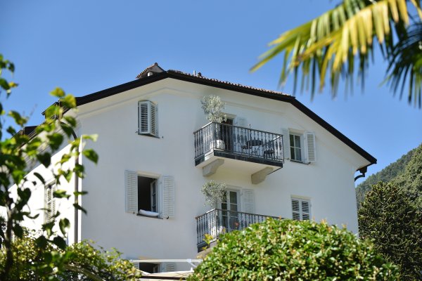 Haus mit weißer Fassade und geöffneten Fenstern und Balkon.