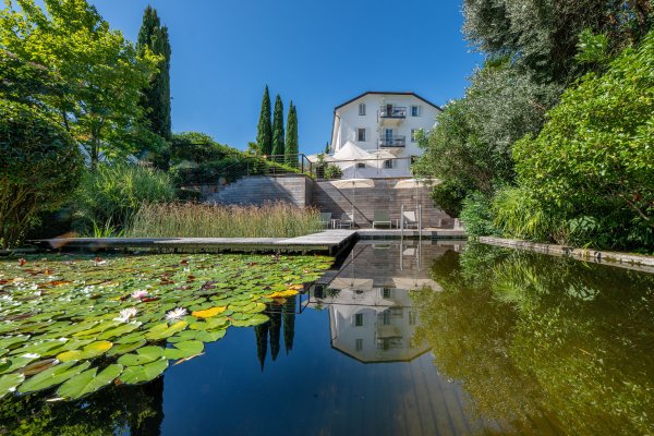 Naturbadeteich in Algund in dem sich das Haus spiegelt.