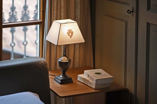 Beistelltisch aus Holz neben grauer Couch mit kleiner Lampe und drei gestapelten Büchern