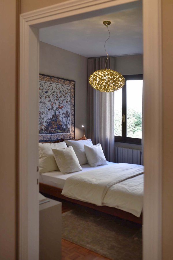 Blick ins Schlafzimmer mit großem Doppelbett und hängender goldener Lampe