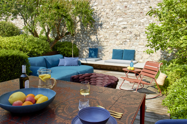 Bunte Gartenmöbel auf einer modernen Terrasse mit einer Schüssel voller Obst und vielen Pflanzen