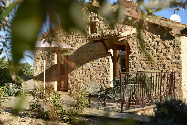 Natursteinhaus mit Terrasse und Sonnenschirm in hügeliger Landschaft