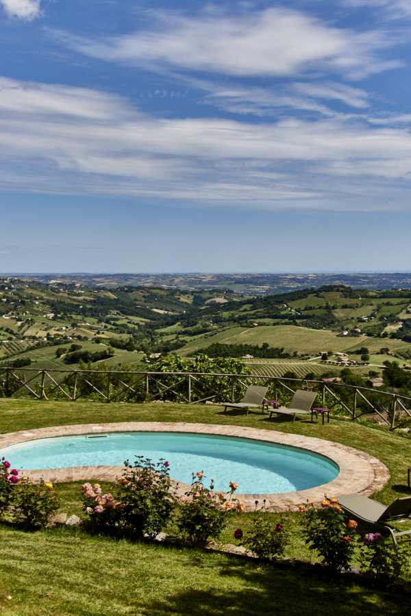 Runder Pool mit Blick auf eine weite Hügellandschaft unter blauem Himmel