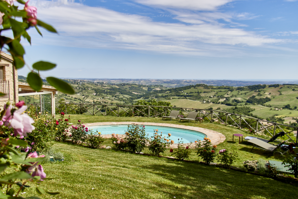 Pool mit Panoramablick auf eine grüne Hügellandschaft unter blauem Himmel