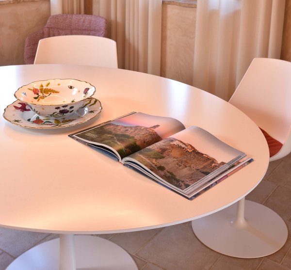 Runder weißer Tisch mit offenem Magazin und dekorativem Geschirr