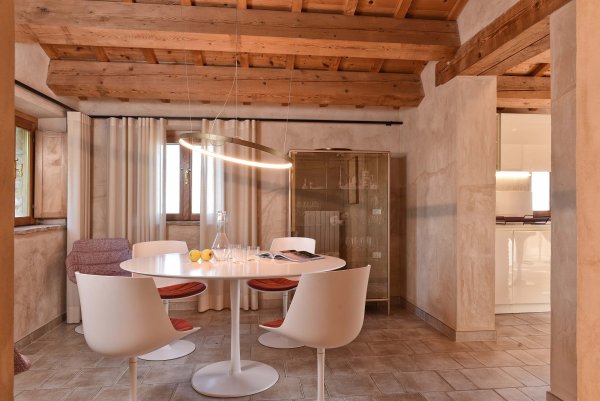 Gemütlicher Essbereich mit rundem weißen Tisch und modernen Stühlen in einem Raum mit Holzbalken