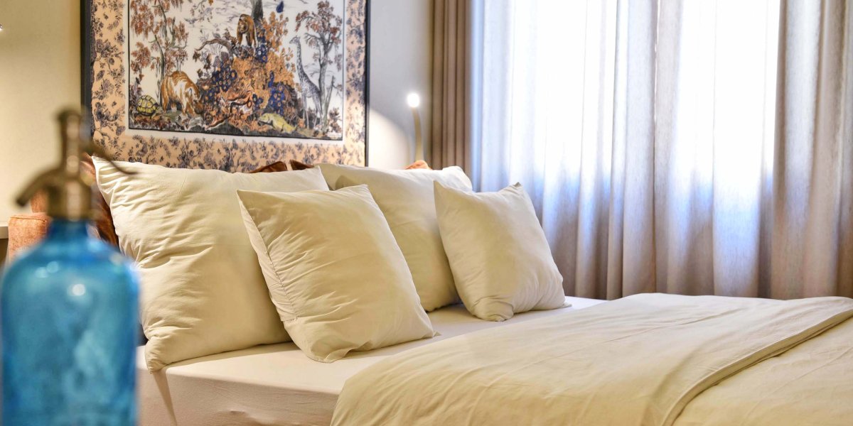 Großes Doppelbett mit weichen Kissen und Kunstbild dahinter an der Wand