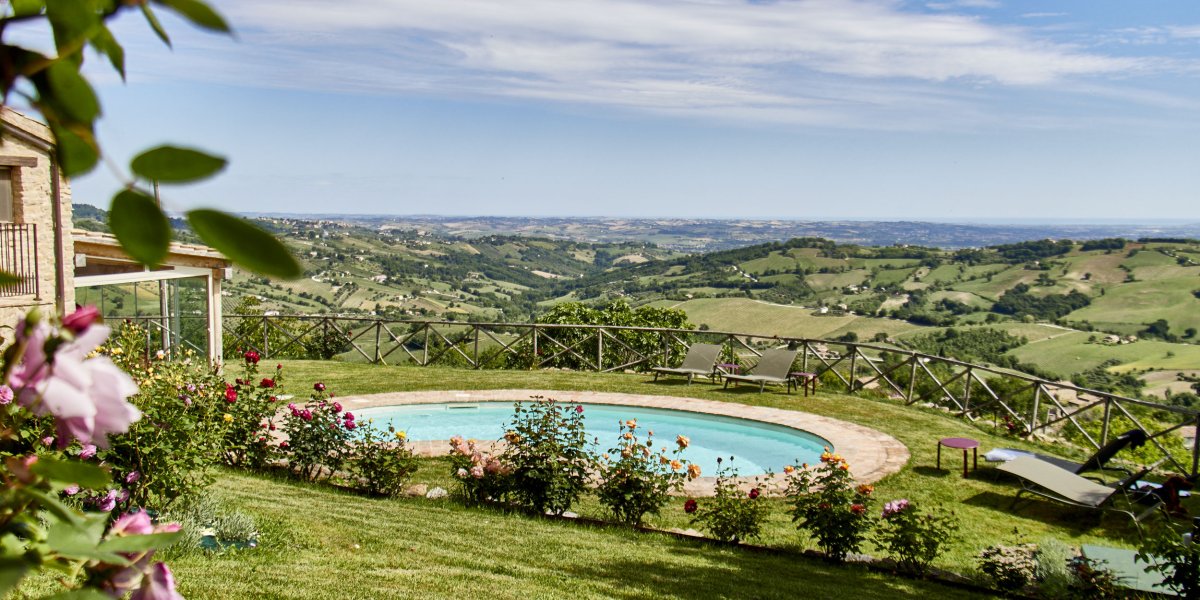 Runder Pool mit Blick auf eine weite Hügellandschaft unter blauem Himmel