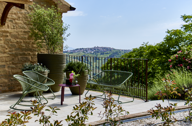 Die sonnige Terrasse mit einem kleinen Tisch und türkisen, stylischen Stühlen, die in der Sonne glänzen
