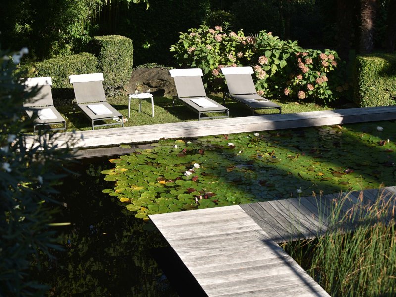Pontile nel laghetto del giardino, quattro lettini sullo sfondo