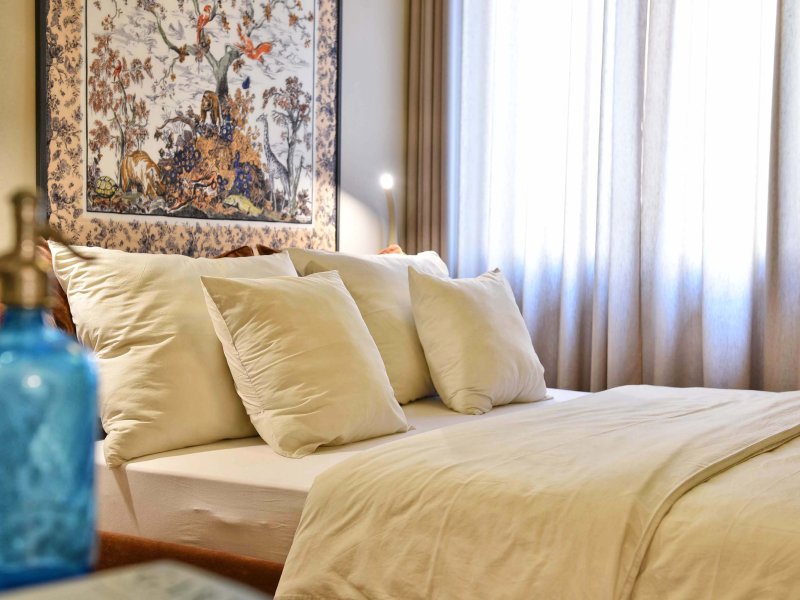 Large double bed with soft pillows and an art piece behind the wall