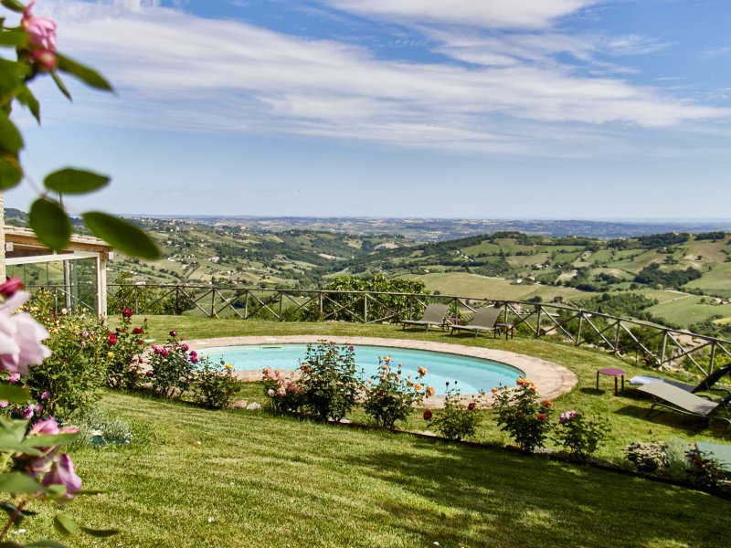 Round pool overlooking a vast hilly landscape under a blue sky